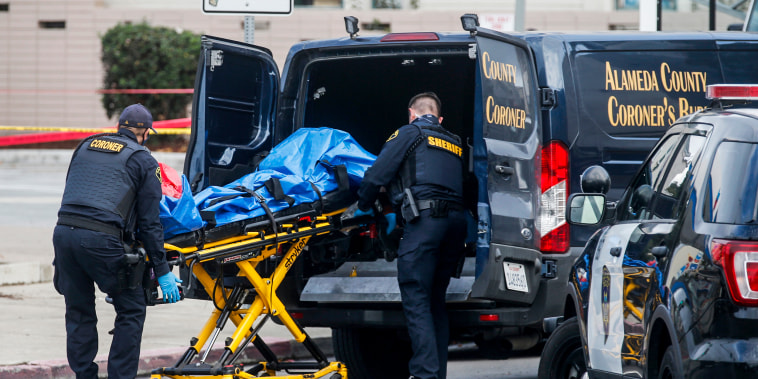 Alameda County Coroner's Bureau deputies remove a victim following a fatal shooting at a gas station in Oakland, Calif.
