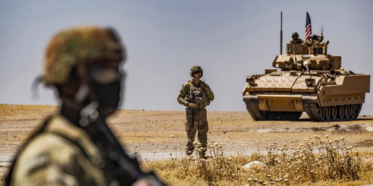 An American soldier stands near a Bradley Fighting Vehicle during a patrol near the Rumaylan oil wells in Syria's northeastern Hasakeh province.