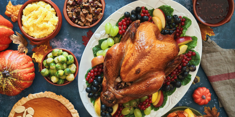 A table covered in Thanksgiving foods, with the roasted turkey front and center.