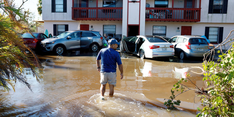 A man walks through flood waters to his apartment in Fort Myers