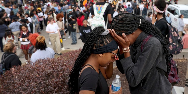Students stand in a parking lot near the Central Visual & Performing Arts High School after a shooting at the school in St. Louis on Oct. 24, 2022. 