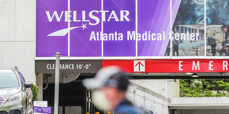 A person wearing a mask walks in front of Wellstar Atlanta Medical Center in Atlanta.
