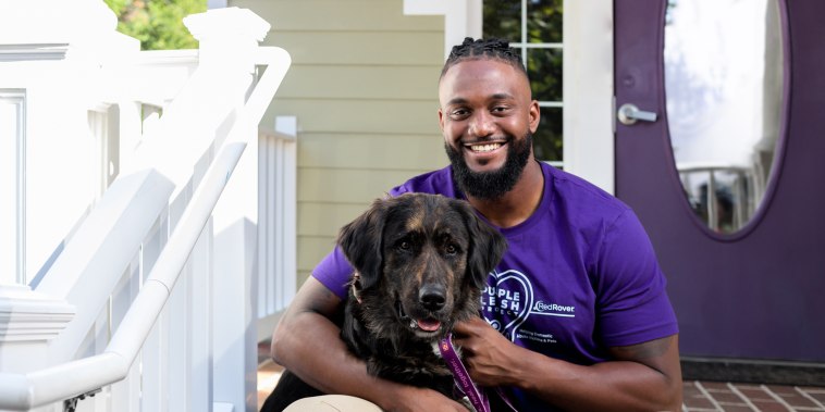 NFL’s James Smith-Williams works sits with a dog on steps