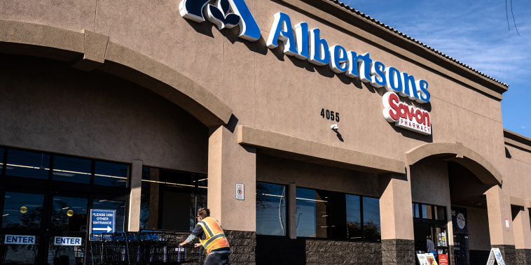 A worker pushes shopping carts outside an Albertsons supermarket in Las Vegas on Jan. 7, 2022.