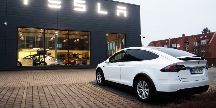 A Tesla Model X in front of a sales shop and service center.
