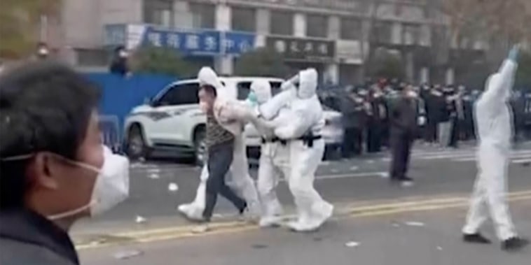 Security personnel take away a person during protest at the Foxconn Technology Group  factory compound