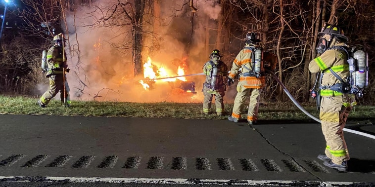Firefighters work to extinguish a burning car in Brookfield, Conn., on Nov. 26, 2022.