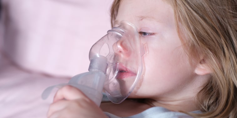 Sick girl in oxygen mask lies on hospital bed