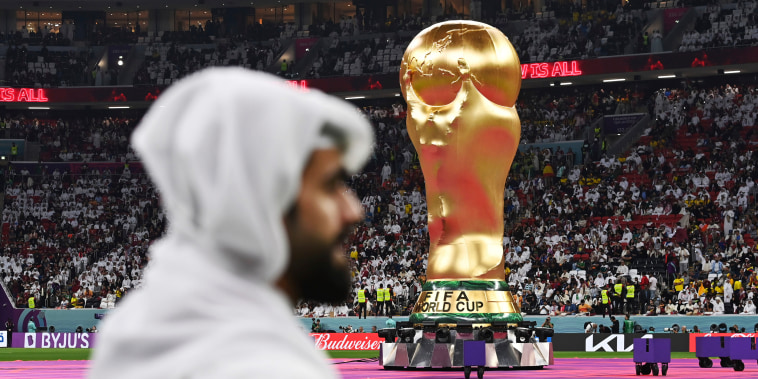 A Qatari stands in front of a huge World Cup trophy Al Bayt Stadium on Nov. 20, 2022. 