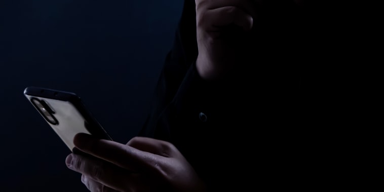 Silhouette of a man using a mobile phone in the dark