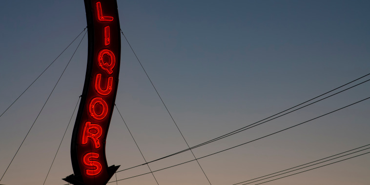 An old-fashioned, red, neon sign that reads "Liquors."