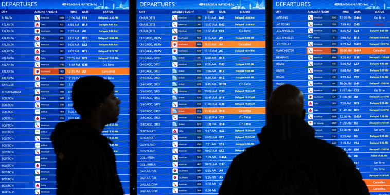 Travelers look at flight information at Ronald Reagan Washington National Airport in Arlington, Va.