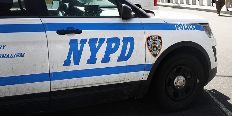 Pedestrians walk past a NYPD vehicle parked in front of One World Trade