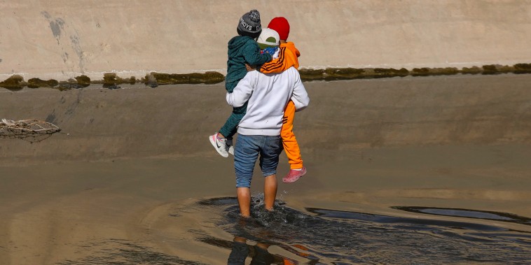 A migrant helps two Venezuelan children to cross the Rio Grande river from Ciudad Juarez, Mexico, to El Paso, Texas, in search of political asylum on Dec. 27, 2022.