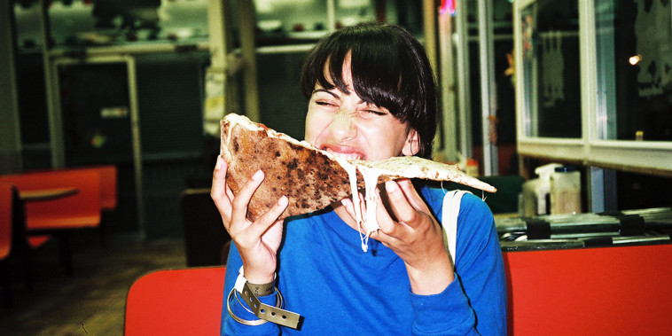Woman eating a large piece of pizza.