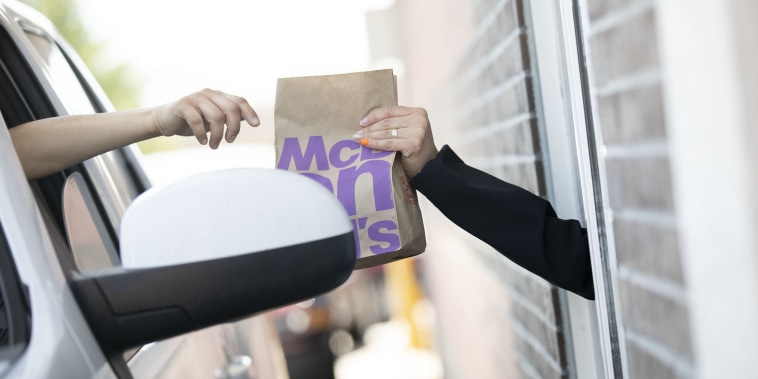 A customer reaches for a bag of food in the drive-through at a McDonald's Corp. restaurant in Peru, Illinois, U.S., on Wednesday, April 8, 2020. Some of America's fast-food workers are finally getting face masks and emergency sick days to help get them through the coronavirus outbreak.