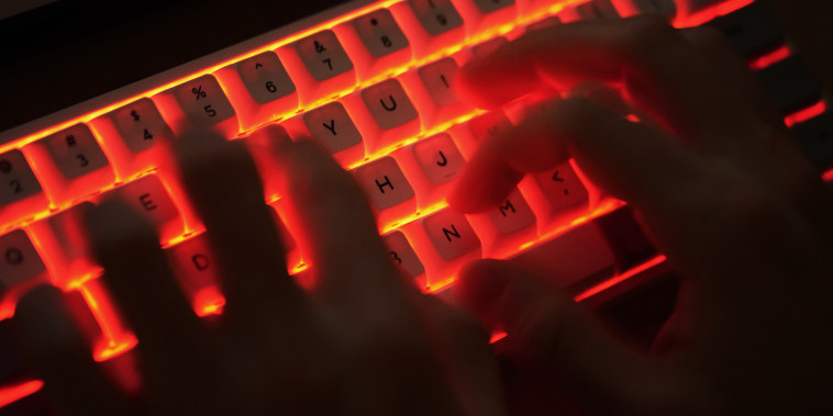 Wire photo of hands typing on an illuminated computer keyboard typically favored by computer coders.