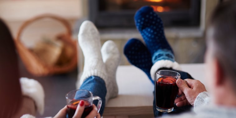 Mature couple with hot drinks in living room at the fireplace