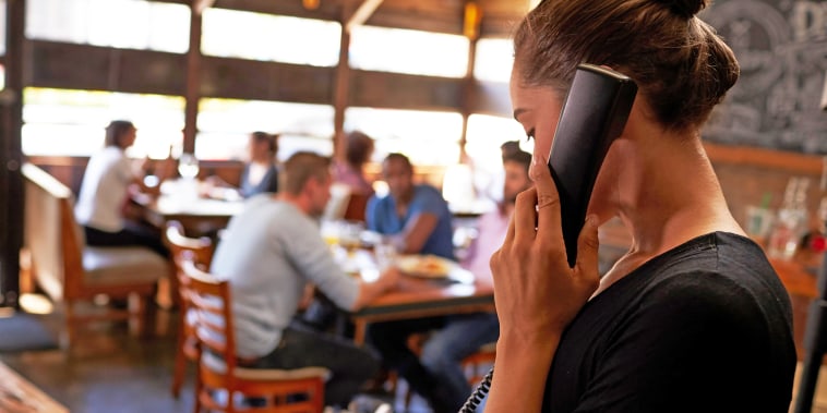 Young woman taking a reservation by phone at a restaurant.