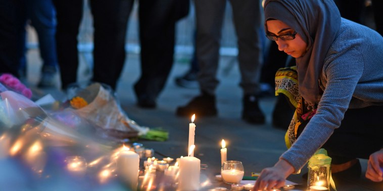 A woman lights candles set up in front of floral tributes in Albert Square in Manchester, England on May 23, 2017, the day after an attack at the Ariana Grande concert at the Manchester Arena.