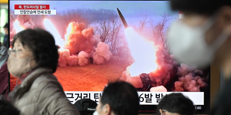 People walk past a television screen showing a news broadcast with file footage of a North Korean missile test, at a railway station in Seoul on March 14, 2023. - North Korea fired two short-range ballistic missiles on March 14, 2023, Seoul said, Pyongyang's second launch in three days and the first since South Korea and the United States began their largest joint military drills in five years.
