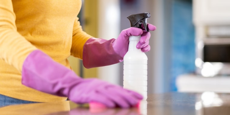 Woman Sanitizing the Counter with Disinfectant and Sponge