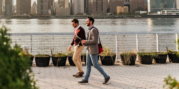 Two young men walking along a river in the city.
