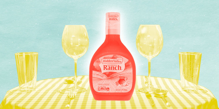 Photo composition of a bottle of ranch on a table with a tablecloth and wine glasses.