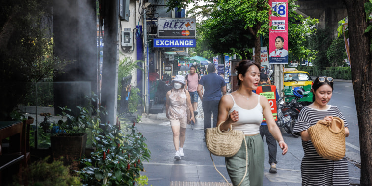 Pedestrians walk past a mist cooling system at a restaurant in Bangkok on April 25, 2023. 