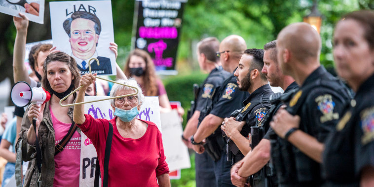 Police officers look on as abortion-rights advocates hold a demonstration outside the home of Supreme Court Justice Brett Kavanaugh on May 18, 2022, in Chevy Chase, Md.