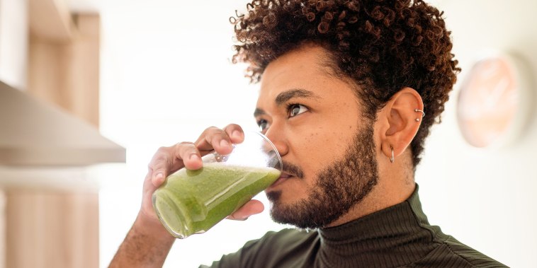 Young man drinking a healthy green smoothie at home.