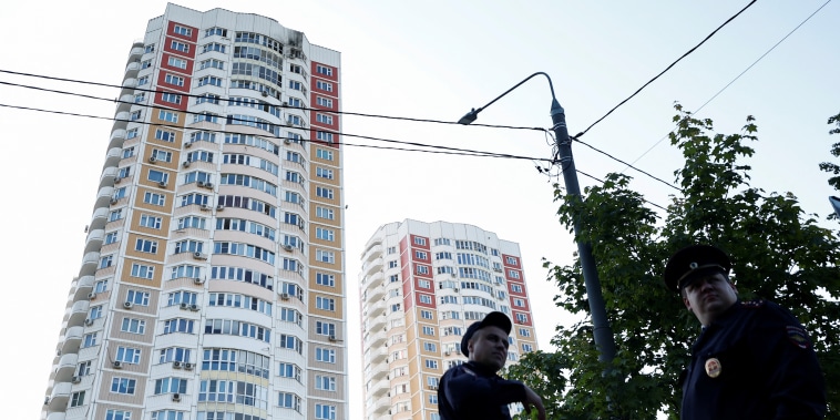 Varios agentes montan guardia cerca de un bloque de apartamentos dañado tras un ataque con drones en Moscú, el 30 de mayo de 2023.