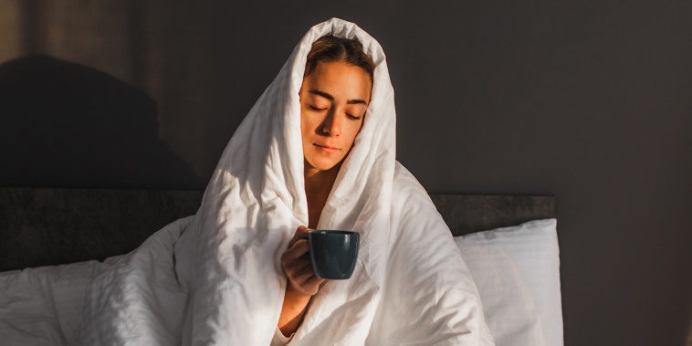 Woman covered in blanket drinking coffee