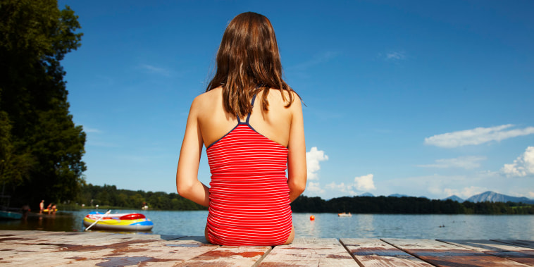 girl sitting on boardwalk at lake in bathing suite