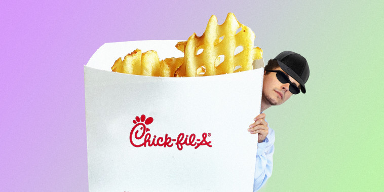Man wearing black hat and sunglasses hiding behind an oversized carton of Chick-fil-a fries