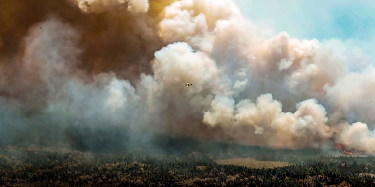Image: One of eight aircrafts from New Brunswick that drops a mix of water and fire retardant makes a pass over the fire near Barrington Lake, Shelburne County, Nova Scotia province on May 31, 2023.
