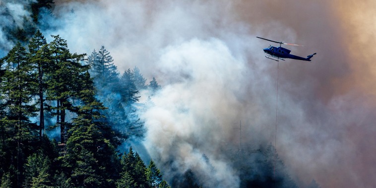 A helicopter drops water onto the Cameron Bluffs wildfire near Port Alberni, Canada
