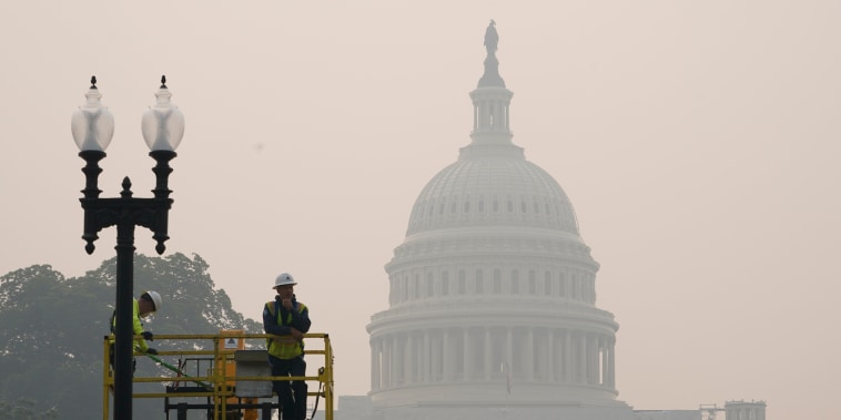 Workers finish tending a street lamp as smoke from Canada wildfires obscures the view of the U.S. Capitol in Washington, Thursday, June 8, 2023. 