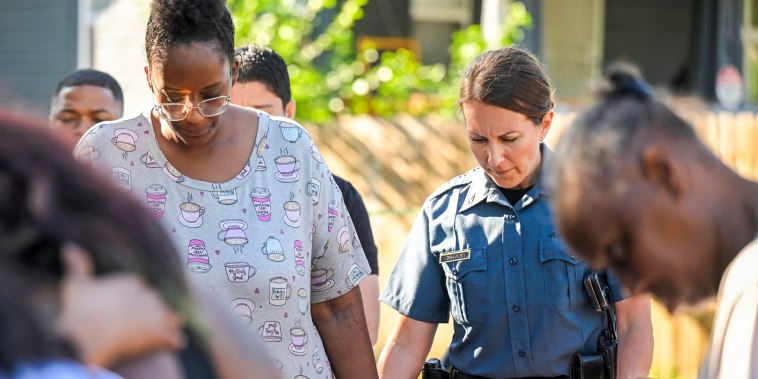 People pray after several people died and others were injured following a shooting in Kansas City, Mo., on June 25, 2023.