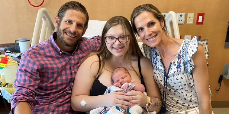 Madelyn holds her baby as they pose with the adoptive parents Nathan Kerr and Laura Robinson.