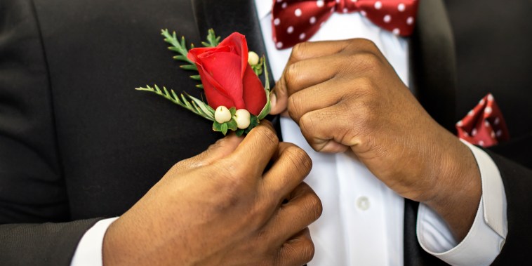 Teen pins his rose boutonniere to formal suit getting dressed and ready for prom.
