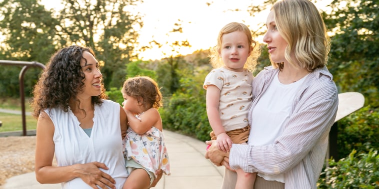 Two young mothers holding their toddlers.