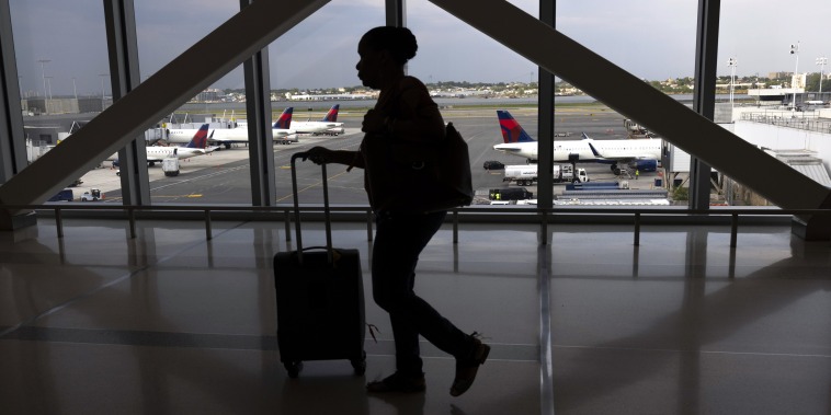A passenger walks past Delta planes on the tarmac at LaGuardia Airport in New York City