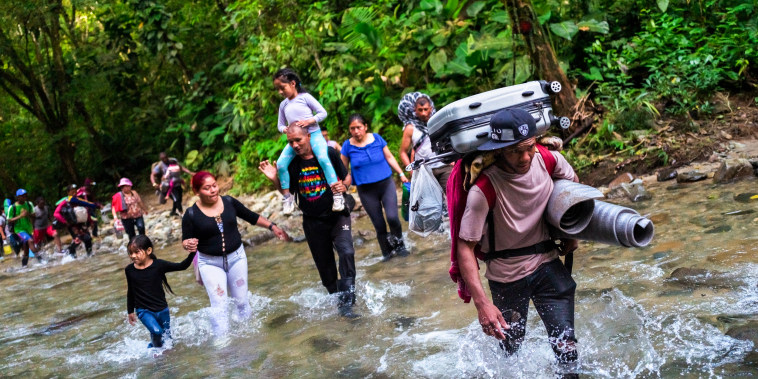 Migrants from Ecuador, Haiti and Nigeria, walk through the river on November 20, 2022 in Darién Gap, Colombia.
