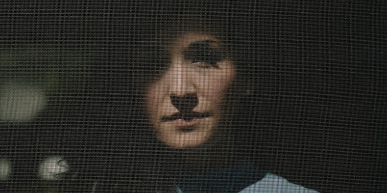 Portrait of Desiree Townsend behind a screen door.