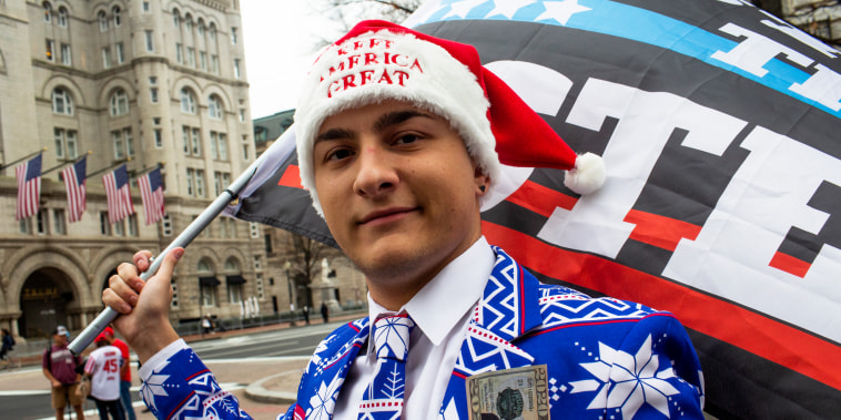 Wearing a red, white, and blue and winter-themed suit, Dylan Quattrucci waves a "Stop the Steal" flag during a rally