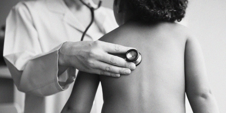 A pediatrician listens to a girl's lungs with a stethoscope.