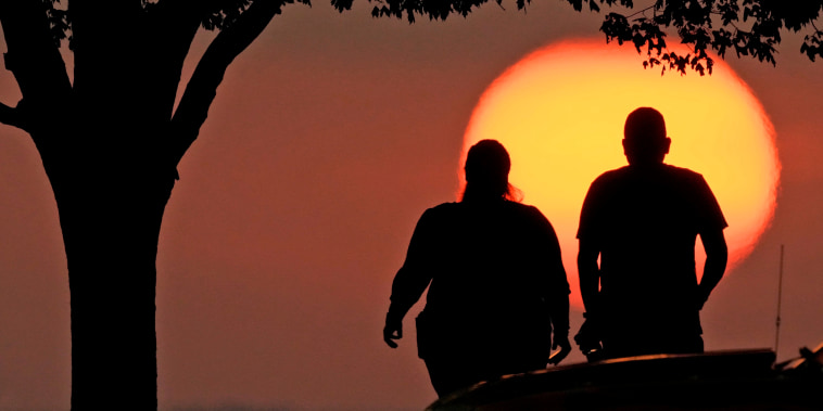 A couple watches the sunset as triple-digit heat indexes continue in the Midwest Sunday, Aug. 20, 2023, in Kansas City, Mo. 