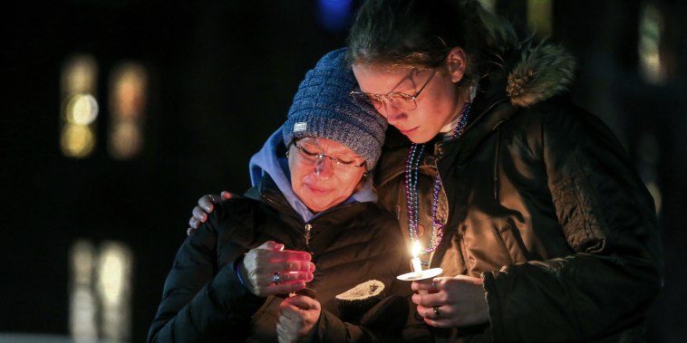 People embrace at a candlelight vigil