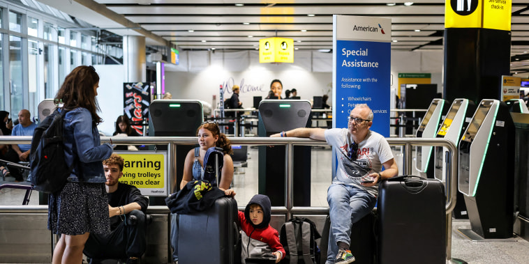 A family waits as their flight delays as Britain's National Air Traffic Service (NATS) restricts UK air traffic due to a technical issue causing delays, in London on Aug. 28, 2023.